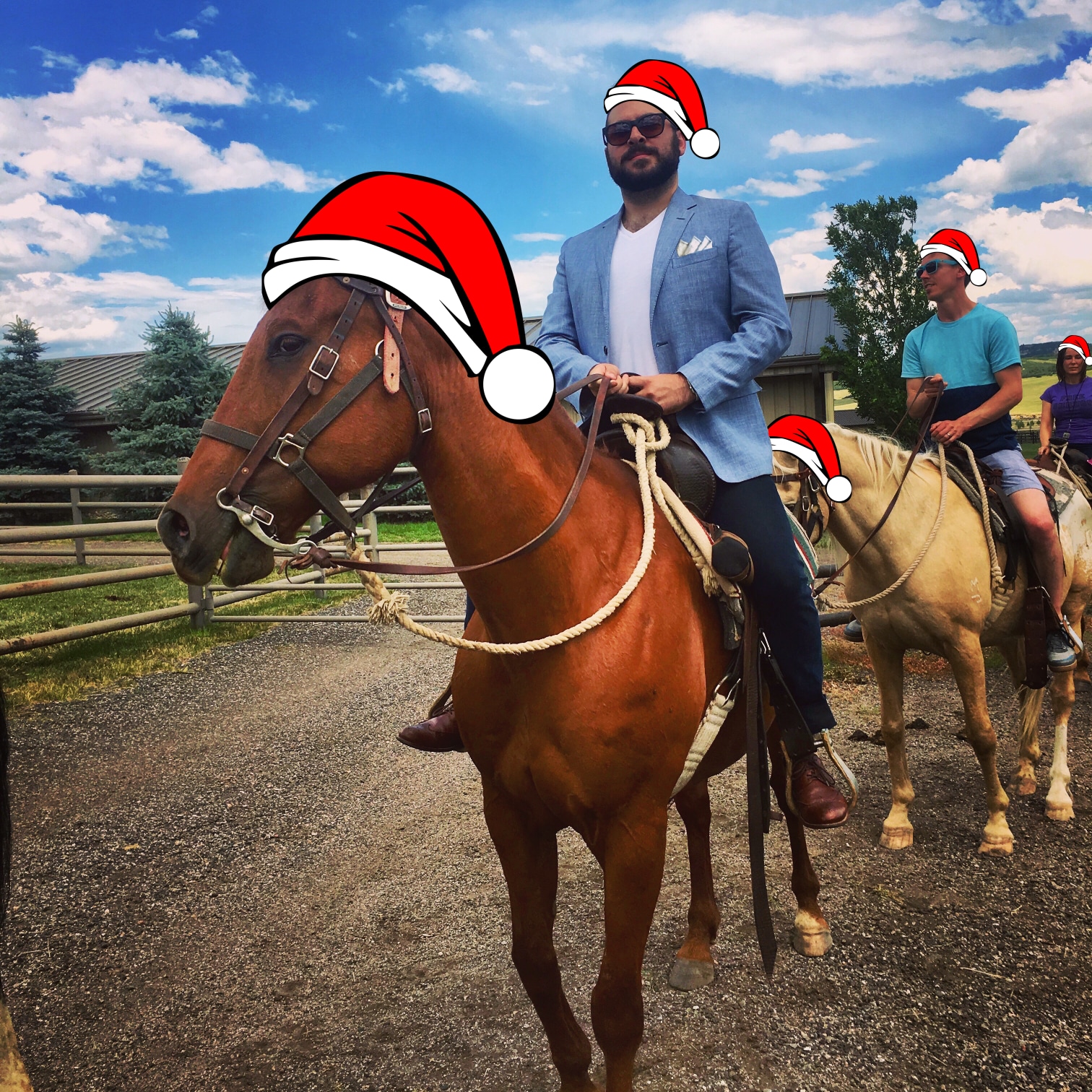A photo of me wearing a blue blazer and pocket square while on a horse, looking quite dapper. Both me and the horse are wearing Santa hats.